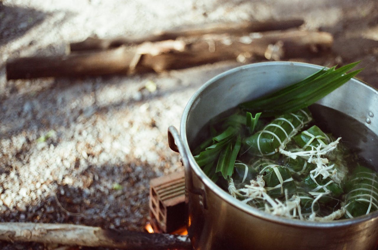 A steaming pot of herbs in an outdoor cooking setup in Vietnam, evoking traditional methods.