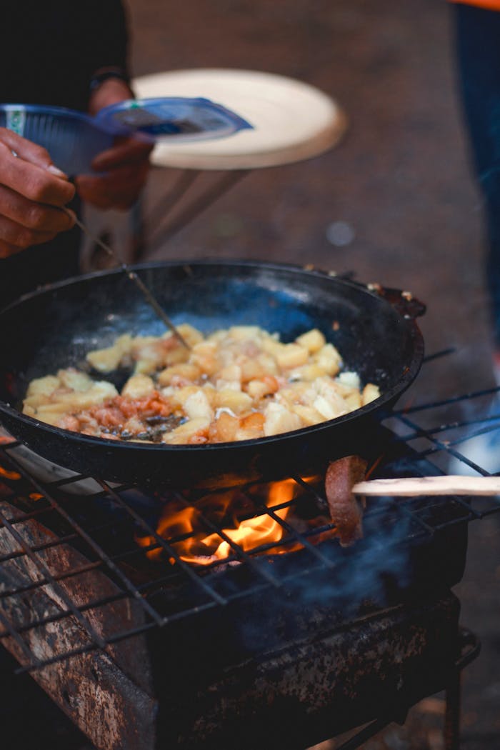 Delicious skillet potatoes cooked over a campfire outdoors, perfect for camping enthusiasts.
