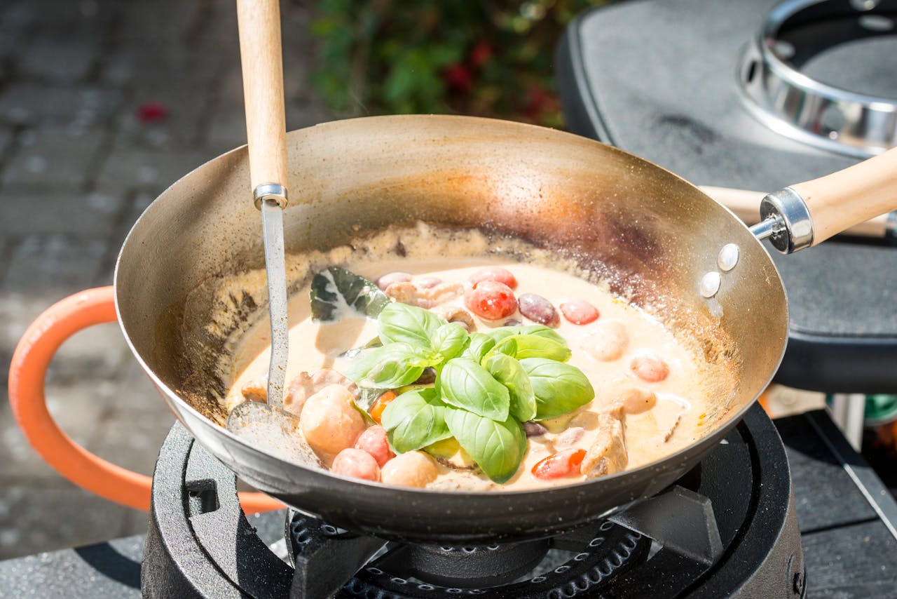 Delicious creamy tomato and basil sauce being prepared in a pan on an outdoor gas stove.